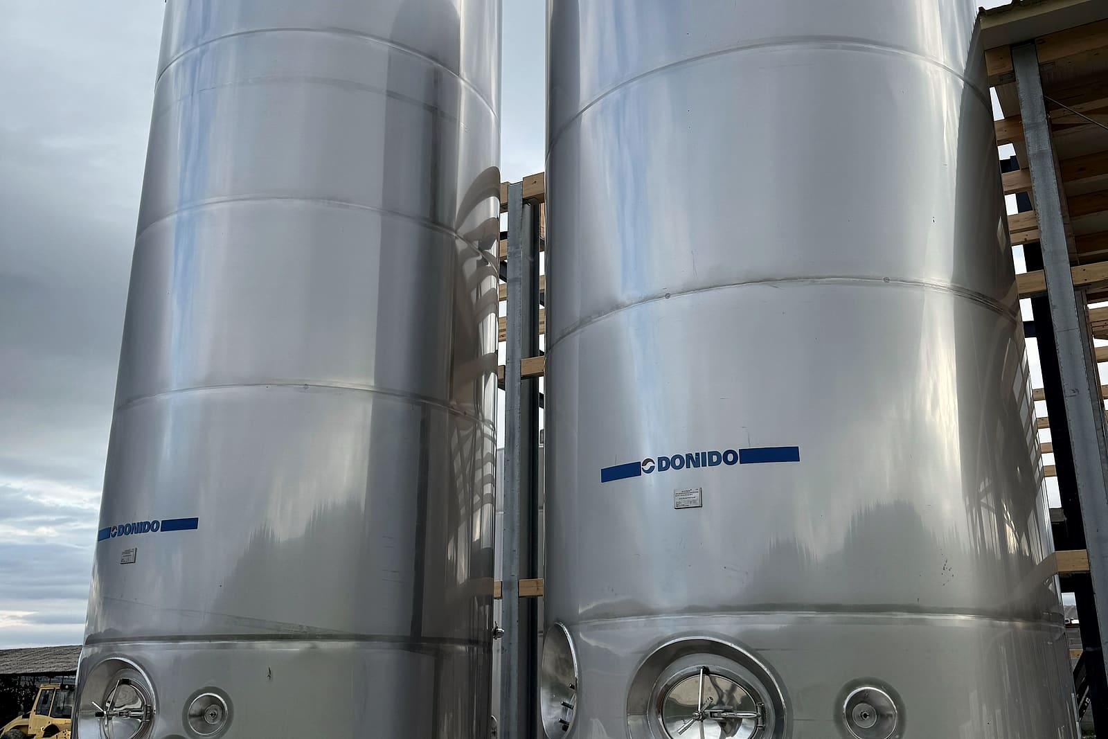 Două silozuri din inox pentru lapte, lângă hală